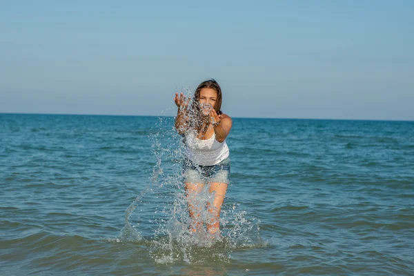 Mladá dívka, stříkající voda v moři — Stock fotografie