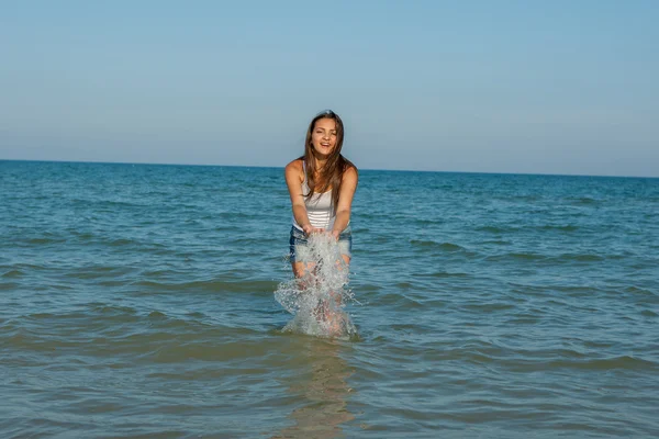 Jovem menina espirrando a água no mar — Fotografia de Stock