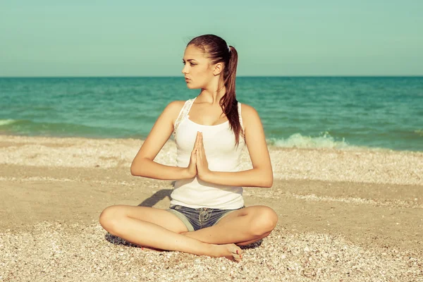Mujer joven practicando yoga o fitness en la orilla del mar — Foto de Stock