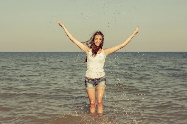 Jong meisje spatten van het water in de zee — Stockfoto