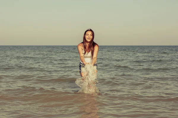 Young girl splashing the water in the sea — Stock Photo, Image