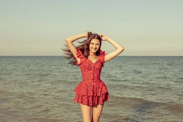 Mladá žena v červených šatech na moři — Stock fotografie