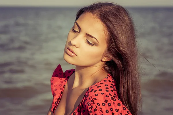 Jeune femme triste près de la mer sur un coucher de soleil — Photo
