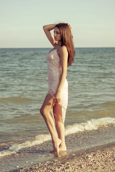 Jovem menina triste perto do mar em um pôr do sol — Fotografia de Stock