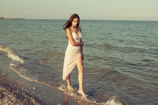 Young sad girl near the sea on a sunset — Stock Photo, Image