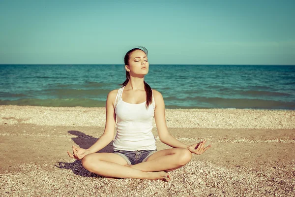 Young woman practicing yoga or fitness at seashore Stock Photo