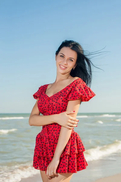 Junges Mädchen im roten Kleid auf dem Meer — Stockfoto