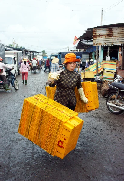 As mulheres carregam bandeja de plástico em seu ombro no mercado de pesca. LONGA HAI, VIET NAM- JULHO 15 — Fotografia de Stock