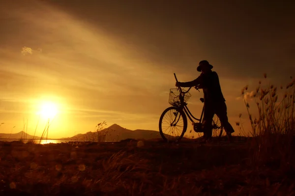 Люди с велосипедом на рассвете — стоковое фото