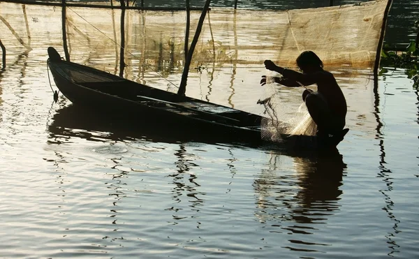 Pescatore seduto sulla barca a remi, prendere la rete — Foto Stock