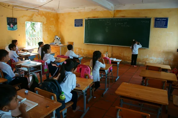 Podstawowy uczeń pisze na tablicy w czasie szkoły — Zdjęcie stockowe