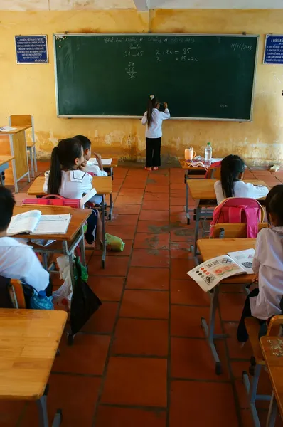 Grundschüler schreiben in der Schulzeit an Tafel Stockbild