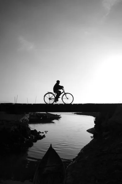 Silhouette of lonely young boy riding bicycle — Stock Photo, Image