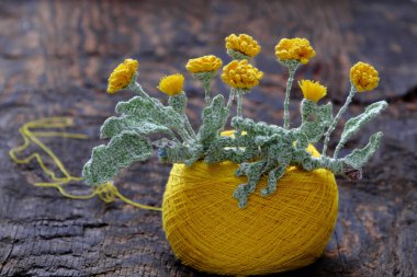 Ev dekorasyonu için güzel sanat eserleri, sarı karahindiba ve ahşap arka planda iplik yumağıyla yeşil yaprak yapmak için tığ işi.