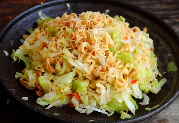 Quick and cheap vegan food for breakfast from instant noodles, fried with cabbage and tomato sauce