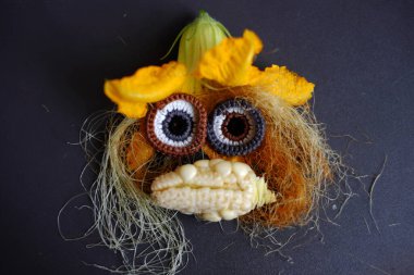 Yemekten yapılmış komik bir yüz, çatı bahçesinden alınmış tarım ürünü, küçük mısır, balkabağı çiçeği, mısır ipeği ve ipekten örülmüş gözler sevimli olur.