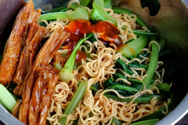 Quick and cheap vegan food for breakfast from instant noodles, fried with kale and tomato sauce