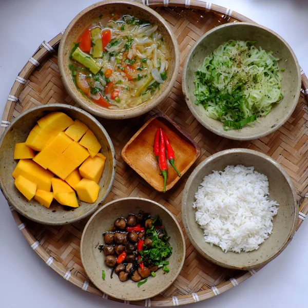 Top view Vietnamese vegan daily family meal for lunch, tray of rice dish with fried chayote, sour soup, straw mushrooms cook with sauce, vegetarian menu with non meat good for health