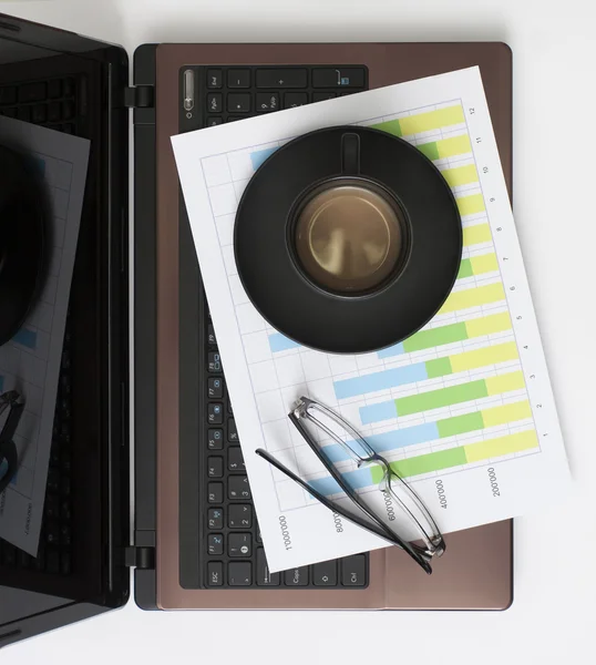 Laptop, grafiek, glazen en koffie — Stockfoto