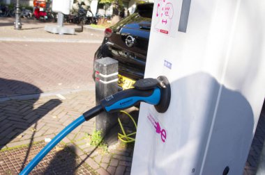 Utrecht, Hollanda - 10 Kasım 2021: Pili şarj etmek için şarj istasyonuna bağlı elektrikli araba