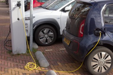 Ede, Hollanda - 30 Ocak 2022: Pili şarj etmek için şarj istasyonuna bağlı elektrikli araba