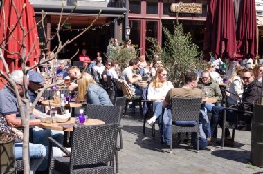 Nijmegen, Netherlands - April 16, 2022: People relax and enjoy a drink at an outdoor cafe terrace in the center of Nijmegen
