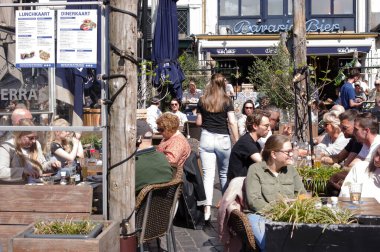 Nijmegen, Netherlands - April 16, 2022: People relax and enjoy a drink at an outdoor cafe terrace in the center of Nijmegen