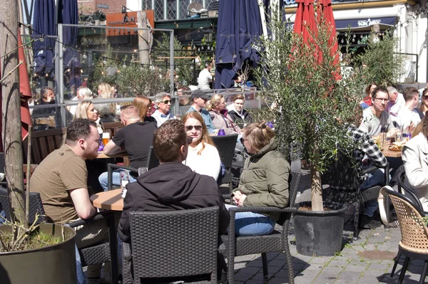 Nijmegen, Hollanda - 16 Nisan 2022: İnsanlar Nijmegen 'in merkezindeki bir açık kafe terasında rahatlayıp içki içiyorlar
