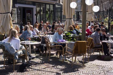 Nijmegen, Netherlands - April 16, 2022: People relax and enjoy a drink at an outdoor cafe terrace in the center of Nijmegen