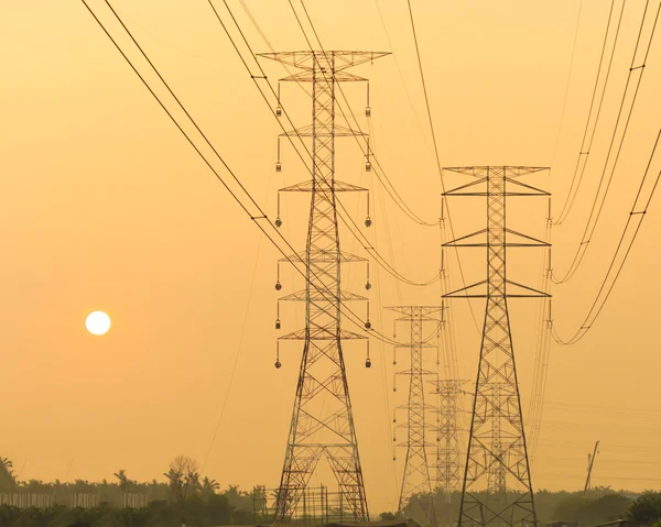 Pyloner och kraftledningar i solnedgången — Stockfoto