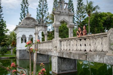 Young Balinese girls dressed in colorful batik sarong in Water Palace Taman Ujung on Bali Island in Indonesia.