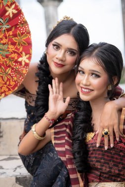Young Balinese girls dressed in colorful batik sarong in Water Palace Taman Ujung on Bali Island in Indonesia.