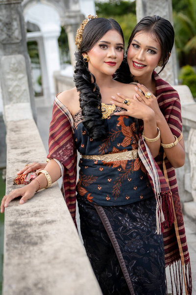 Young Balinese girls dressed in colorful batik sarong in Water Palace Taman Ujung on Bali Island in Indonesia.