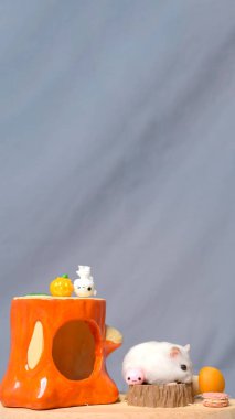 Turuncu eviyle birlikte gri arkaplanlı hamsterın fotoğraf stüdyosu.