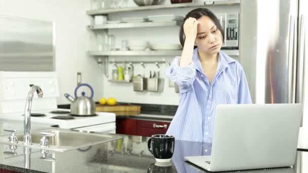 Asiatisk tjej med en laptop i köket — Stockvideo