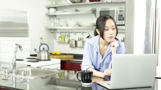 Asian girl with a laptop in the kitchen — Stock Video