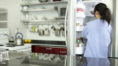 Asyalı kız bir pastayı buzdolabından alır.