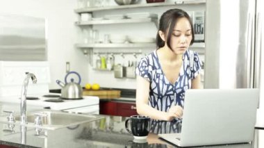 Asyalı kız mutfakta bir dizüstü bilgisayar ile
