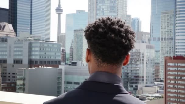 Hombre de negocios afroamericano mirando un edificio de la ciudad — Vídeo de stock