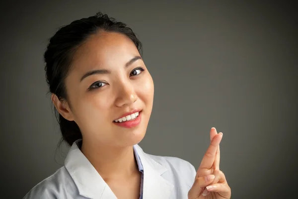 Attractive asian girl nurse with crossed fingers — Stock Photo, Image