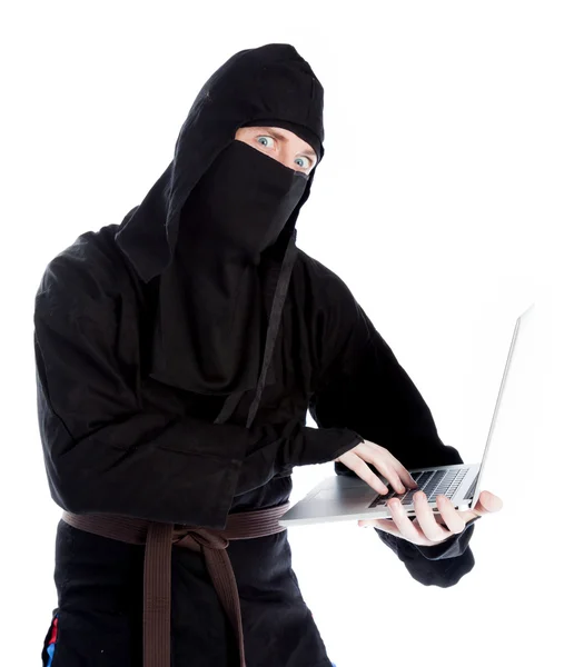 Attractive caucasian man in a ninja suit holding a laptop — Stock Photo, Image
