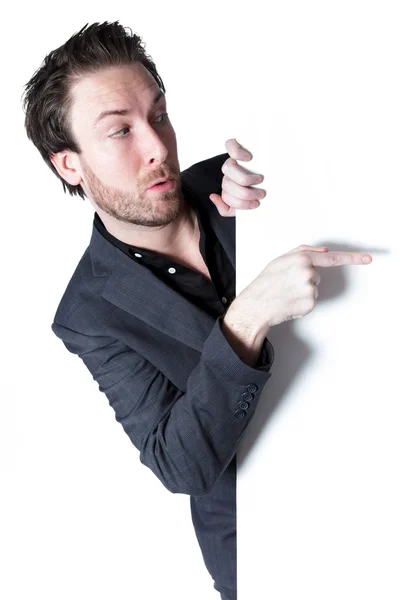 Attractive caucasian businessman points with his finger on a large blank of white paper — Stock Photo, Image