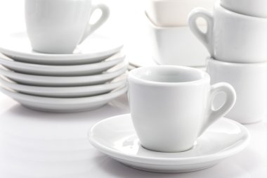 Beyaz arka planda izole edilmiş espresso bardakları ve çay tabakları.