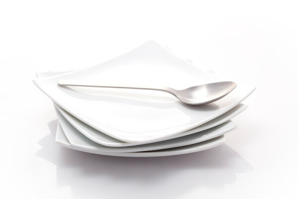 stack of square plates with a spoon isolated on a white backgrou