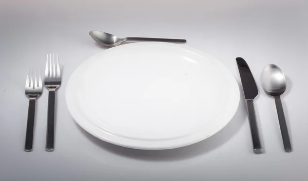 Белая тарелка с вилкой, ножом и ложкой — стоковое фото