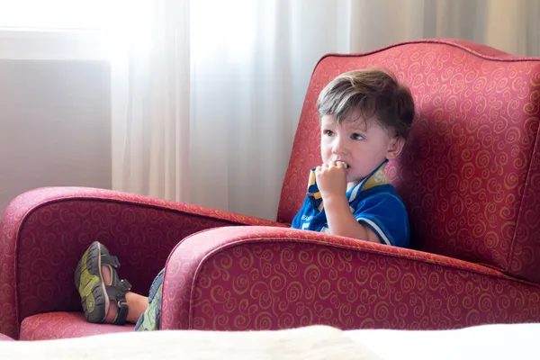 Niño en un sillón rojo —  Fotos de Stock