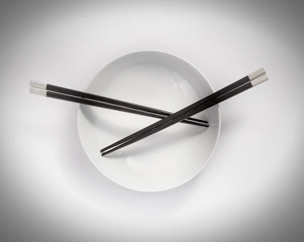Black chopsticks in empty bowl — Stock Photo, Image