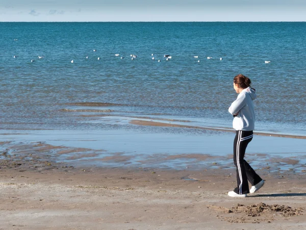 Frau geht am Strand spazieren — Stockfoto