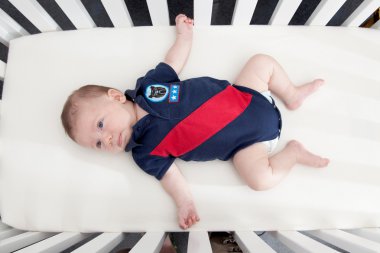 Baby boy lying in a crib clipart