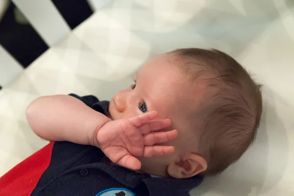 Baby boy lying in a crib — Stock Photo, Image